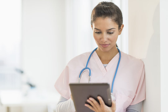 Female nurse using digital tablet while standing in hospital