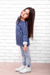 Little girl on a white brick wall background