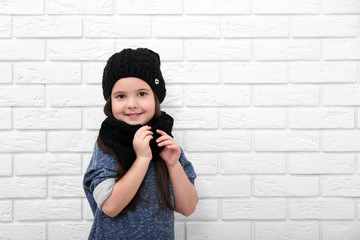 Little girl on a white brick wall background