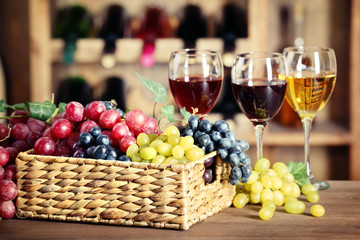 Grape in wicker box on a table on wine bottles background