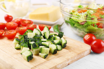 Female hands cutting vegetables for salad, at kitchen