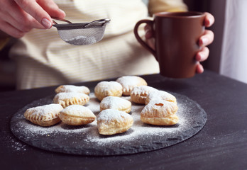 Cook is powdering heart shaped biscuits