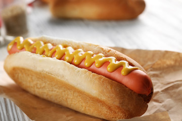 Hot dog on craft paper on wooden background, closeup