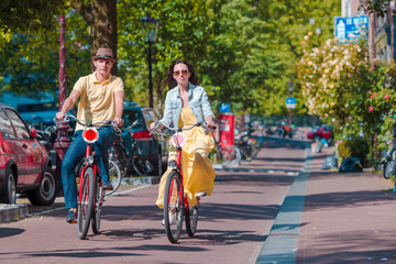 Young happy caucasian couple on bikes in old streets in Amsterdam