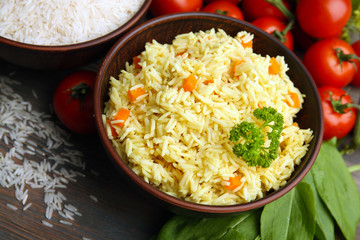 Bowls of rice and vegetables on wooden table closeup