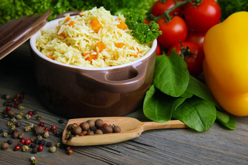 Pan of vegetarian rice with vegetables and allspice on wooden table closeup