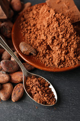 Bowl with aromatic cocoa beans and chocolate on grey background, close up