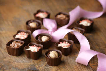 Set of chocolate candies with ribbon on a wooden background