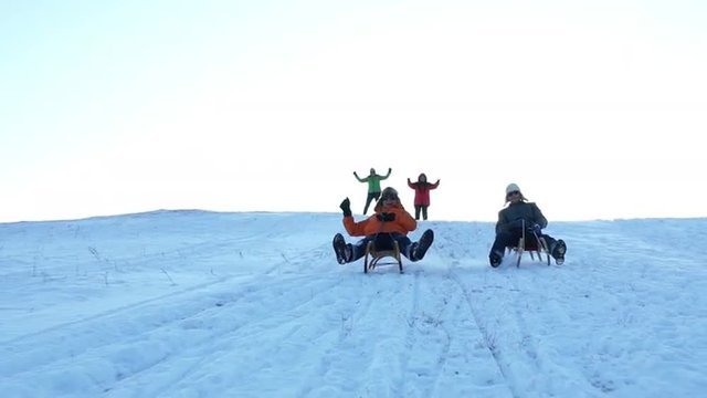 very happy active senior men tobogganing on sunny winter day, wives cheering on snowy hilltop, slow motion
