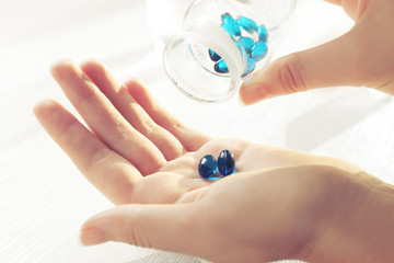 Transparent blue pills in female hands