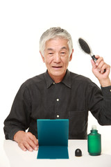 senior Japanese man using hair restorer