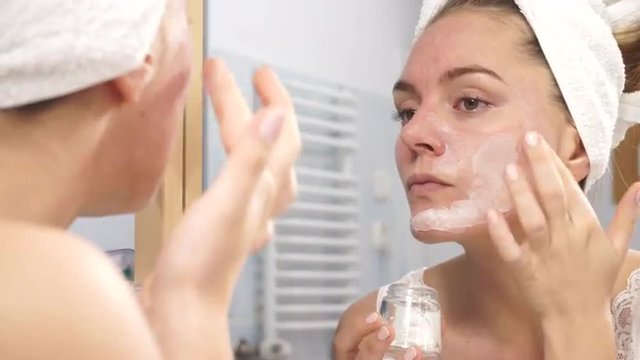 Woman applying mask cream on face in bathroom 4K