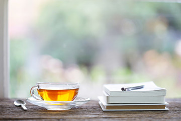 tea in glass and notebook with pencil at windows