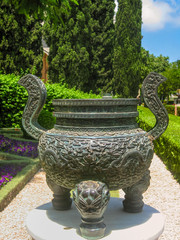 Bahai garden with blossoming flowers and bronze  vase sculpture. Haifa, Israel.
