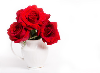 Three red roses in a white vase on a white background