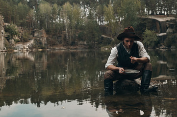 unshaved golddigger washes gold in the lake with rocky bank 