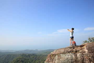 Obraz premium young woman backpacker taking photo with camera on mountain peak