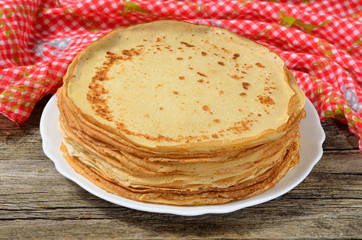 Stack of pancakes on old wooden table with red tablecloth