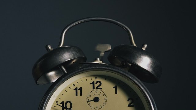 Vintage alarm clock ringing, clock face detail with ringing bells.