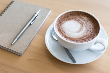 Coffee cup and notebook on grunge wooden background