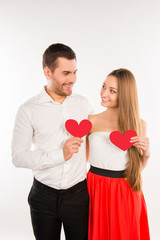 Cheerful couple in love holding two red paper hearts