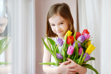 Adorable smiling little girl with tulips