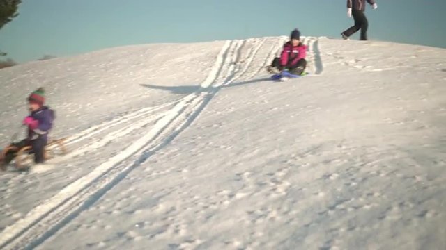 4k footage, young girls sledding on sunny winter holiday afternoon
