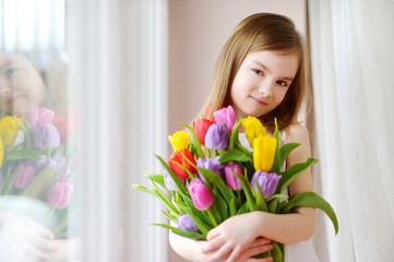 Adorable smiling little girl with tulips