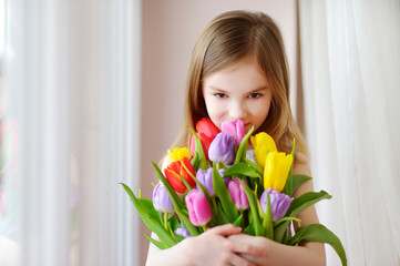 Adorable smiling little girl with tulips