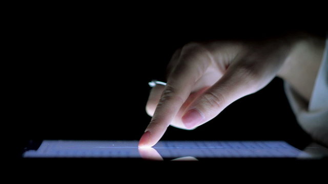 Close-Up of Female Hand on the Ipad Screen in the Dark