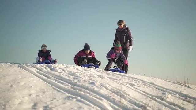 4k footage, young girls ready for tobogganing with bobsleds on snowy hill on sunny winter day
