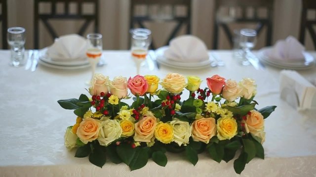 Table decorated with roses flowers. Served tables in small cozy restaurant for event celebration. Wedding reception table set awaiting guests.