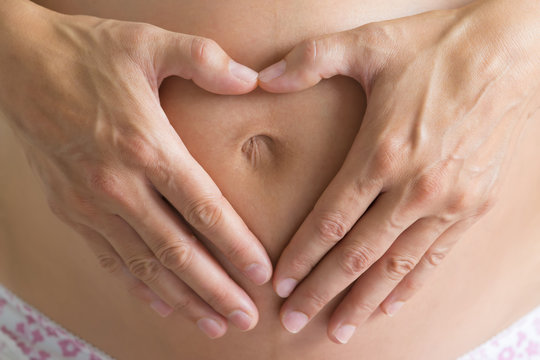 Embarazada haciendo un coraz&oacute;n con sus manos sobre su barriga