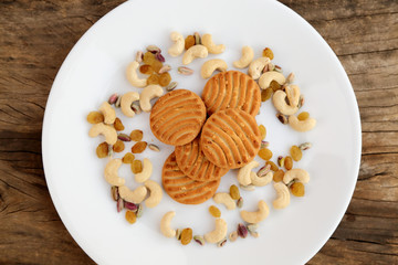 cookies on plate with dry fruits on grey wooden background