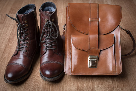 Men's boots and brown bag on wooden table