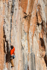 Young man climbing on a limestone wall with wide valley on the background