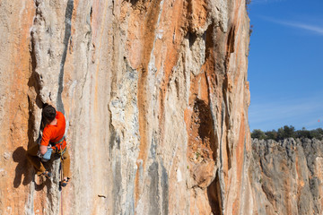 Young man climbing on a limestone wall with wide valley on the background