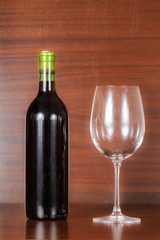 Glass of red wine with a bottle isolated on wood background