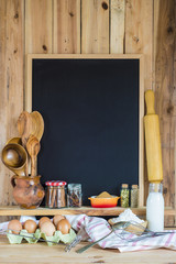 Pizarra de fondo negro con espacio vacío para texto decorada con utensilios de cocina e ingredientes de repostería y pastelería