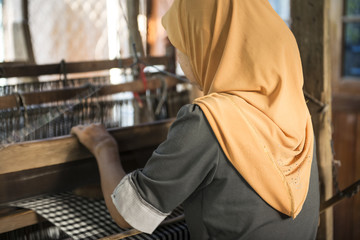 Fototapeta na wymiar Mujer musulmana de espalda trabajando en un telar manual. Vietnam