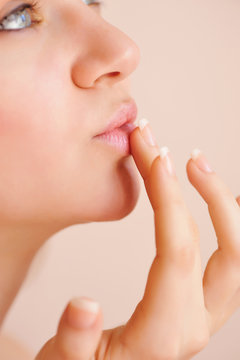 Attractive young woman applying lip balm