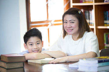 Obraz premium Portrait of happy boy and teacher reading book by bookshelf in l