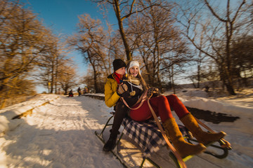 Couple play in winter with snow and sledges