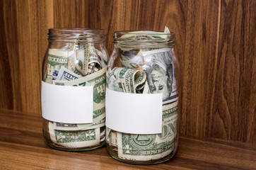 empty label off glass jars with dollar on wooden background - savings and  financial concept