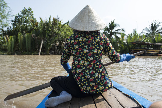 Chica vietnamita de espalda con gorro tradicional, navegando por el río Mekong, Vietnam