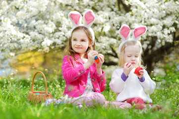 Obraz na płótnie Canvas Two adorable little sisters playing with Easter eggs on Easter day