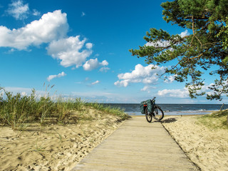 A touring bicycle stands on a wooden path along the Baltic Sea coast.