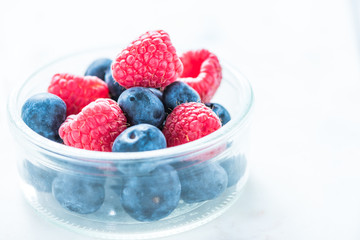 Pot with fresh berry fruits on white