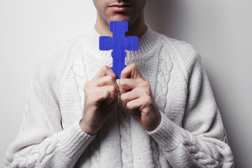 young man holding cross praying