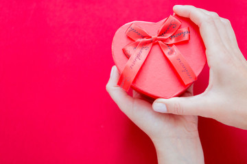Woman hands holding red heart-shaped box